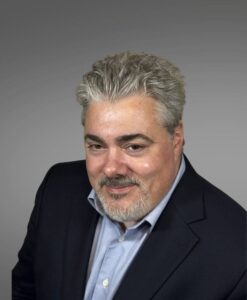 medical provider, blue business jacket, blue collared shirt, gray hair, beard