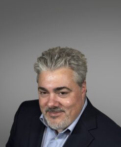 medical provider, blue business jacket, blue collared shirt, gray hair, beard