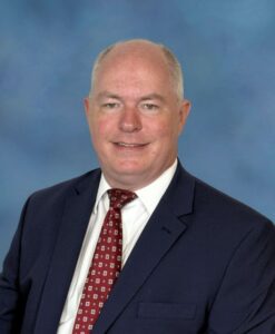 Male, Blue suit jacket, white shirt, red patterned tie.