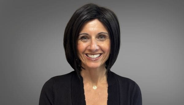 julie hardies. female, black short hair, black sweater, necklace